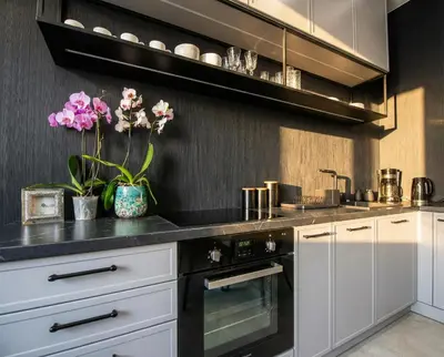 a kitchen with white cabinets and black appliances at City Lights Skawińska in Kraków
