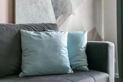 a gray couch with two blue pillows on it at Premium Apartment in Kossak Residence in Kraków