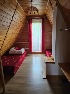 a attic room with a red bed and a window at LESNA CHATA - jestesmy 15km od Energylandii, domek wolnostojacy, Beskid Maly in Zagórnik