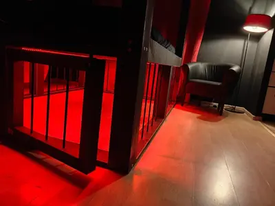 a black chair sitting in a room with red light at BDSM Elysium Playsuite in Kraków