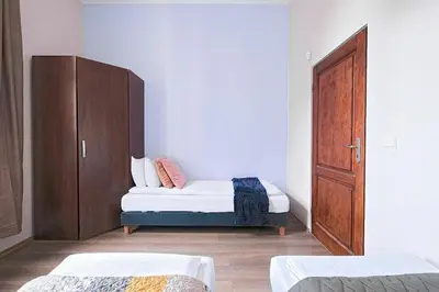 a bedroom with two beds and a wooden cabinet at Urban Nest Apartments Gertrudy 7 in Kraków