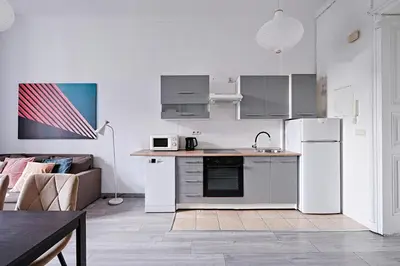 a kitchen with white appliances and a living room at Urban Nest Apartments Gertrudy 7 in Kraków