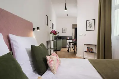 a bedroom with a bed with white sheets and green pillows at Rajska Residence in Kraków