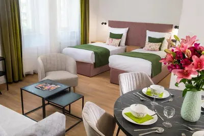 a hotel room with two beds and a table with flowers at Rajska Residence in Kraków
