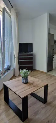 a living room with a table and a kitchen at Cosy Apartment w pobliżu Tauron Arena in Kraków
