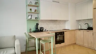 a kitchen with white cabinets and a table and chairs at Castle Apartments - Queen in Oświęcim