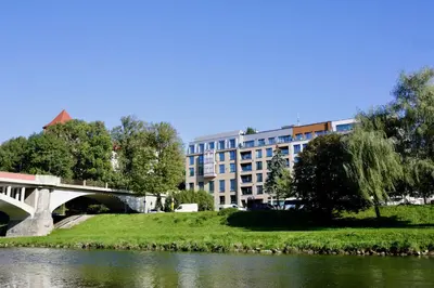 a building next to a river with a bridge at Castle Apartments - Queen in Oświęcim