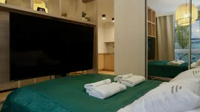 a bedroom with a flat screen tv and two towels at Castle Apartments - Queen in Oświęcim