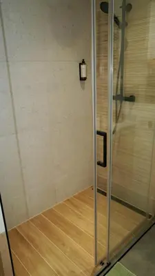 a shower in a room with a wooden floor at Castle Apartments - King in Oświęcim