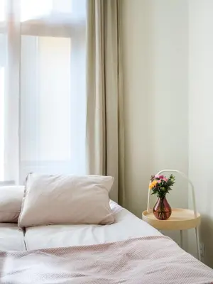 a bedroom with a bed and a vase of flowers on a table at Bed & Beige Apartment / Kochanowskiego St in Kraków