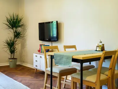 a dining room with a table and chairs and a tv at Bed & Beige Apartment / Kochanowskiego St in Kraków