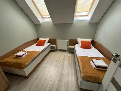 two beds in a small room with two windows at Apartamenty u Edzi in Zator