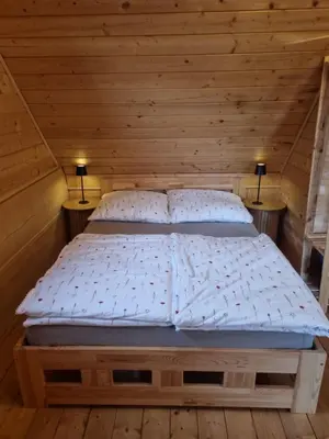 a bed in a wooden room with two lamps at Domek w drapie in Lubomierz