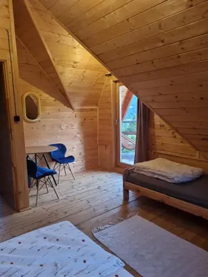 a room with a bed and a table and chairs at Domek w drapie in Lubomierz