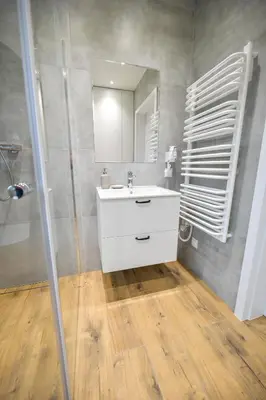 a bathroom with a white sink and a mirror at Comfort Apartments Oświęcim in Oświęcim