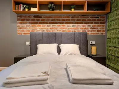 a bedroom with a large bed with a brick wall at Bonerowska 5 by Homeprime in Kraków