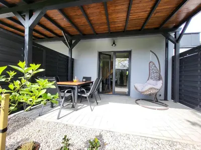 a patio with a wooden roof and a table and chairs at Lipowy Zakątek - domki blisko Energylandii i stacji PKP w Zatorze in Zator