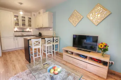 a living room with a television and a kitchen at Ekskluzywny Apartament w centrum z balkonem i parkingiem in Kraków