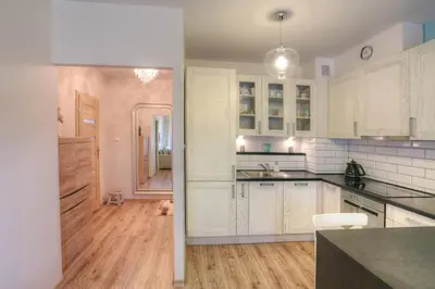 a kitchen with white cabinets and a wooden floor at Ekskluzywny Apartament w centrum z balkonem i parkingiem in Kraków