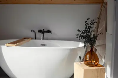 a white bath tub with a vase on a wooden box at Babia Rest - całoroczny domek z balią z jacuzzi in Zawoja