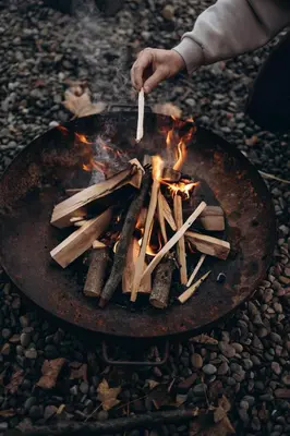 a person holding a spatula over a fire at Babia Rest - całoroczny domek z balią z jacuzzi in Zawoja