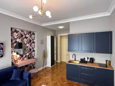 a kitchen with blue cabinets and a living room at Premium Apartment in Spiski Palace in Kraków