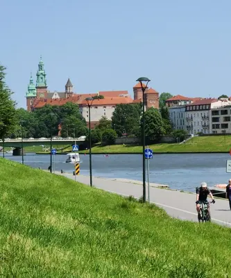 a man riding a bike on a road next to a river at Luxury Apartments, self check in 24 h & Free Parking in Kraków