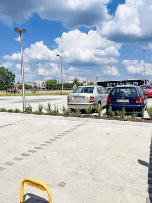 a yellow chair in a parking lot with two cars at Nowohucka Apartament in Kraków