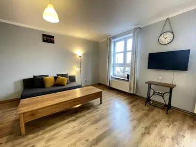 a living room with a couch and a clock on the wall at Bianca Studio in Kraków