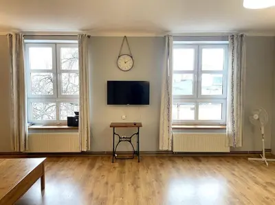 a living room with a clock on the wall and windows at Bianca Studio in Kraków