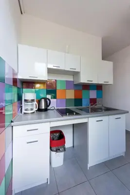 a kitchen with white cabinets and a colorful tile wall at Bianca Studio in Kraków