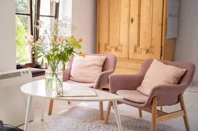 a living room with two chairs and a table with a vase of flowers at Tomte - scandinavian apartment in Kraków