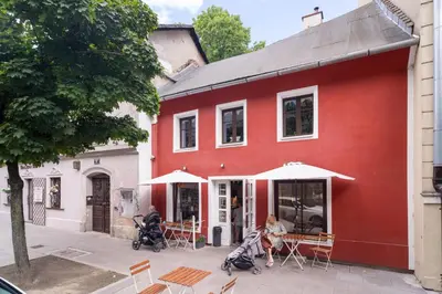 a red building with tables and chairs in front of it at Tomte - scandinavian apartment in Kraków