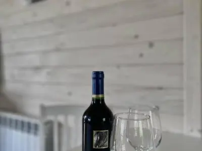 a bottle of wine sitting next to two wine glasses at Domek Leniuchowo in Rabka