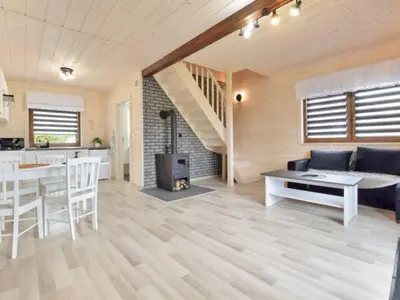 a kitchen and a living room with a table and chairs at Domek Leniuchowo in Rabka