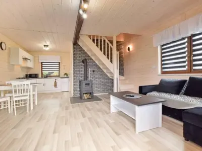a living room with a couch and a table and a kitchen at Domek Leniuchowo in Rabka