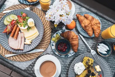 a table with plates of food and croissants and coffee at Tukan Old Town in Kraków