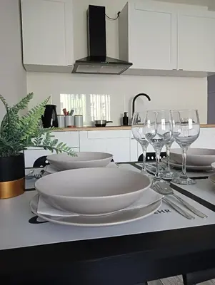 a table with white plates and wine glasses on it at Apartamenty Oświęcim klimatyzacja air-conditioned in Oświęcim