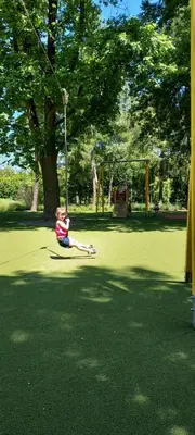 a young girl sitting on a swing in a park at Apartamenty Oświęcim klimatyzacja air-conditioned in Oświęcim
