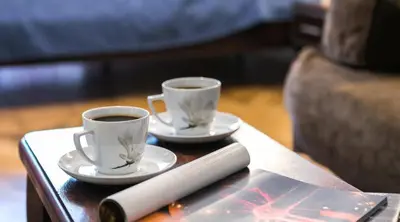 two cups of coffee and a remote on a table at Apartments Legendary Kraków in Kraków