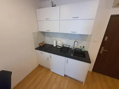 a small kitchen with a sink and white cabinets at Apartments Legendary Kraków in Kraków