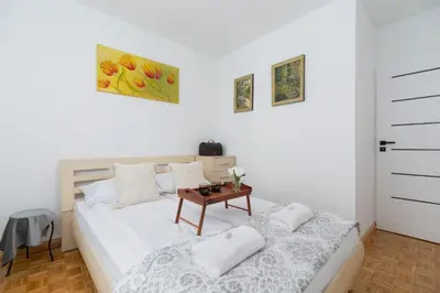 a white bedroom with a bed and a table at Ruczaj Apartment Cracow Dębniki by Noclegi Renters in Kraków