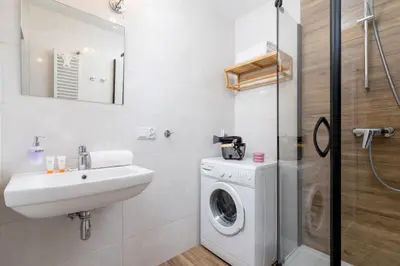 a bathroom with a washing machine and a sink at Ruczaj Apartment Cracow Dębniki by Noclegi Renters in Kraków