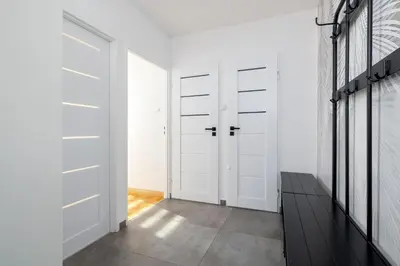 a hallway with white closet doors and a black bench at Ruczaj Apartment Cracow Dębniki by Noclegi Renters in Kraków
