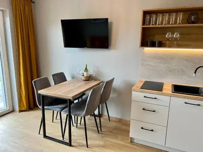 a kitchen with a table with chairs and a tv at Jaśminowa Park in Zator