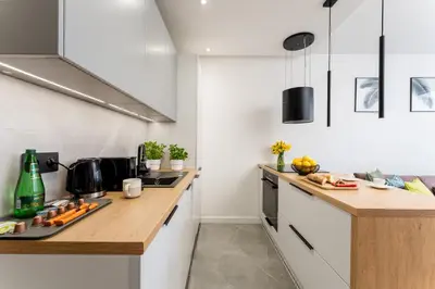 a kitchen with white cabinets and a wooden counter top at Verona House - Premium Apartment in Kraków