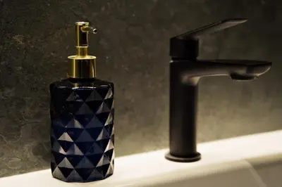 a bottle of soap sitting on a sink next to a faucet at Apartament Thaddeus 48 z tarasem in Zator