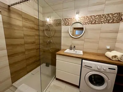a bathroom with a washing machine and a shower at Tresor Pułaskiego Apartments in Kraków