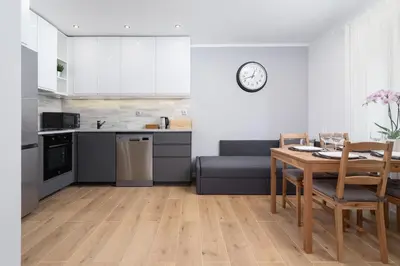 a kitchen and living room with a table and a couch at Cosy and Comfortable Apartment in Krakow by Noclegi Renters in Kraków