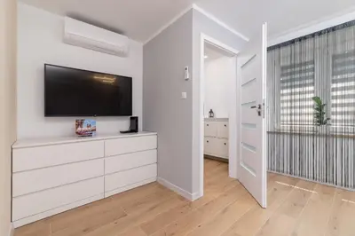 a living room with a flat screen tv on a white wall at Cosy and Comfortable Apartment in Krakow by Noclegi Renters in Kraków